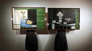  Art handlers pose with "Nature morte" and "Nature morte aux volets verts" by Pablo Picasso at Christie's auction house in London